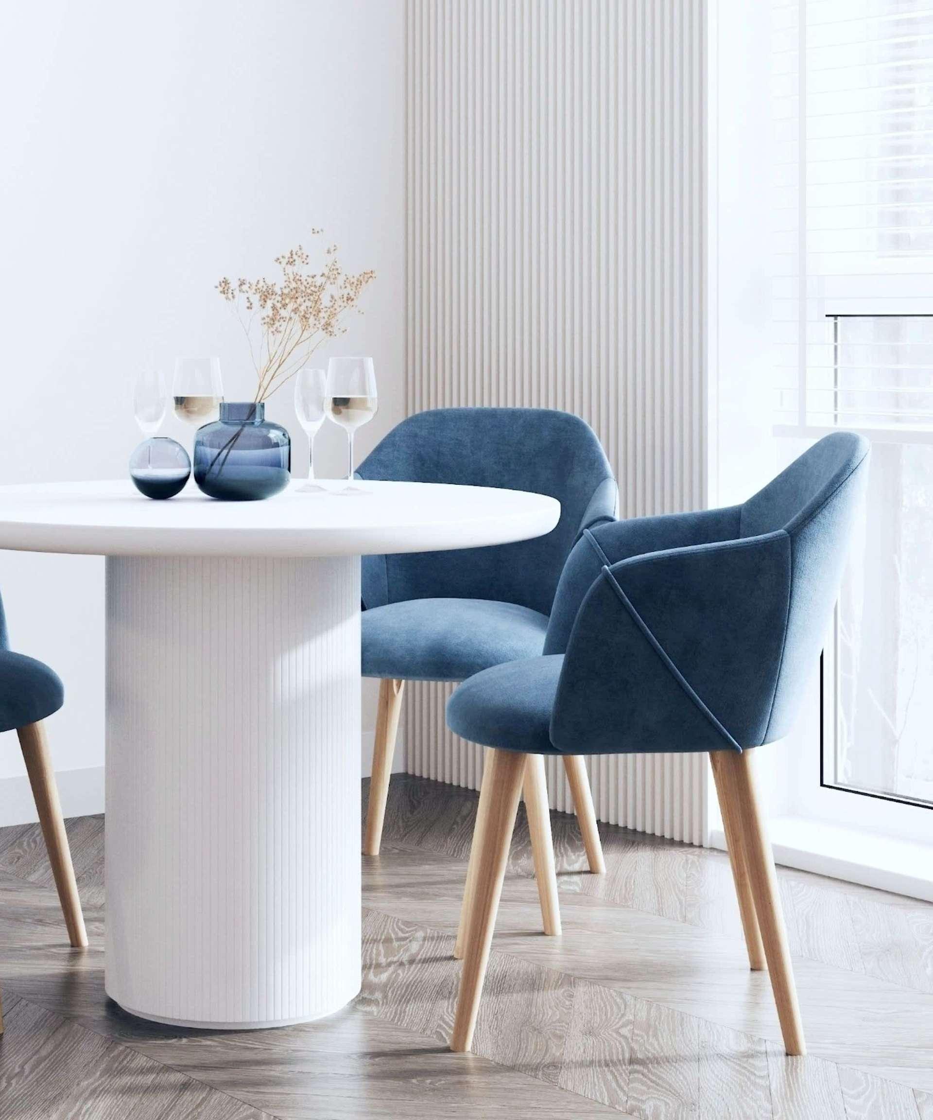 Modern dining nook with blue velvet chairs and round white pedestal table